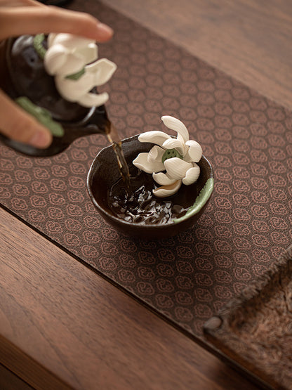 One lotus tea cup pouring tea into a matching cup during a serving demonstration