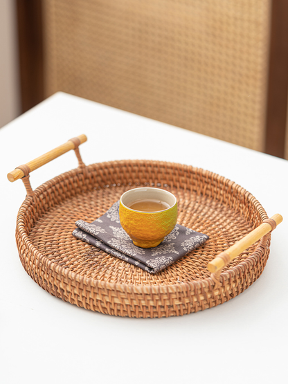 Tangerine-shaped ceramic teacup filled with amber tea on a woven serving tray