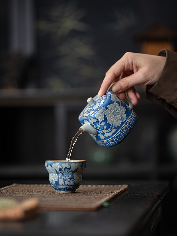 Blue peony crackle glaze teapot pouring tea into a blue floral cup
