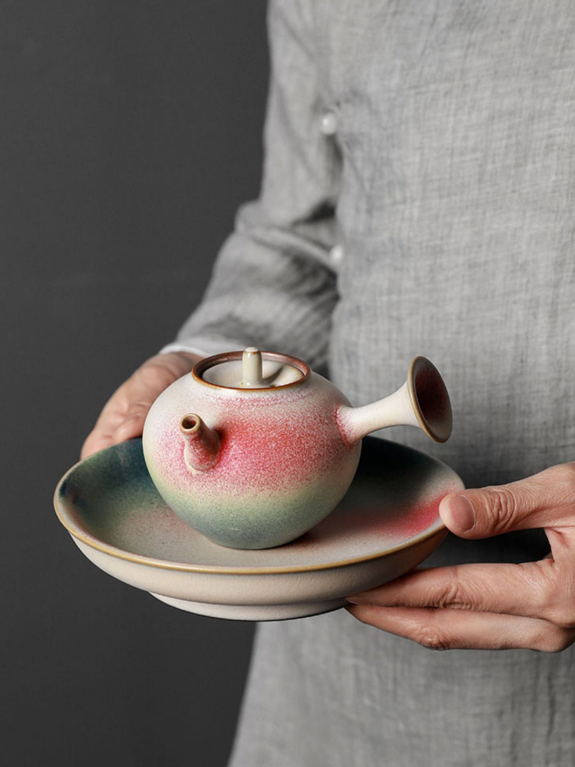 Side-handle ceramic teapot held on a matching ceramic tray