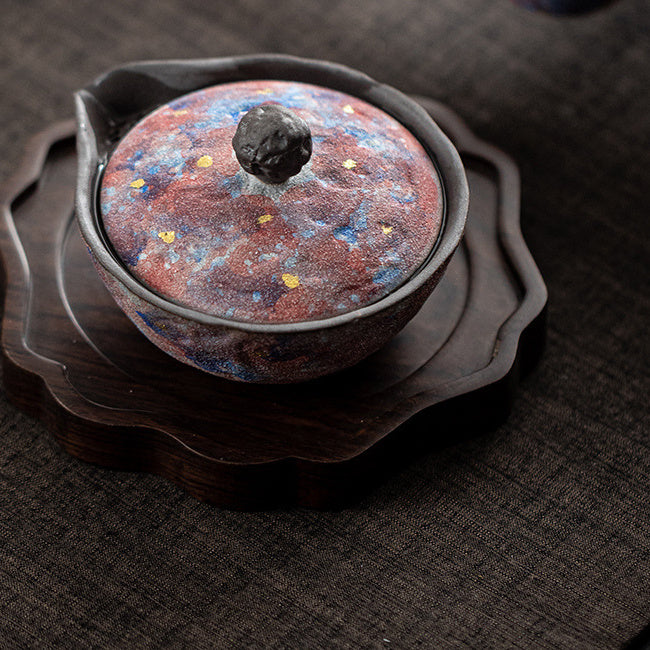 Galaxy glaze ceramic teapot displayed on a carved wooden tea tray
