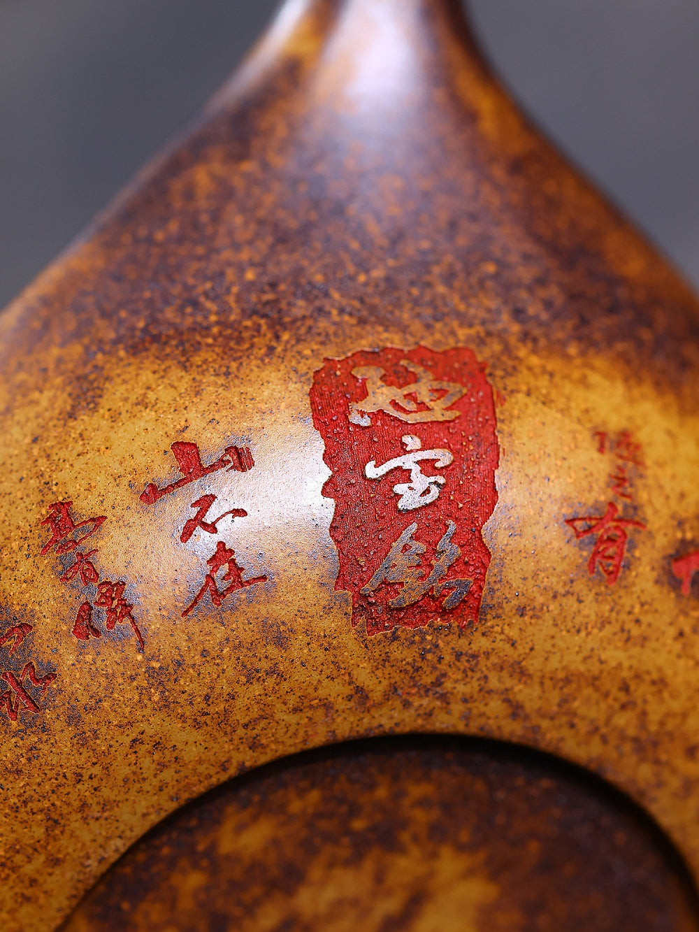 Close-up of the Yixing zisha teapot base with Chinese inscriptions and mottled wood-fired texture
