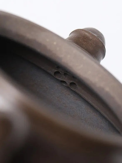 Close-up of the seven-hole outlet inside a bronze-brown zisha teapot