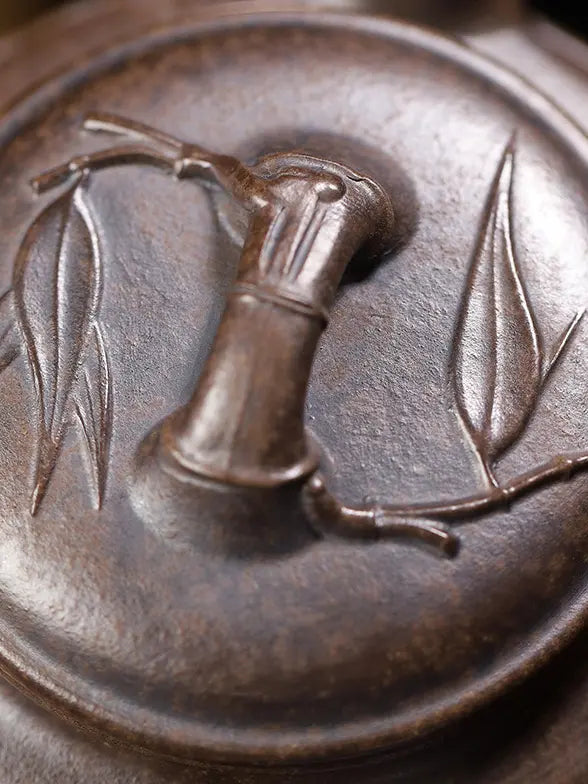 Close-up of the bamboo-joint lid knob and carved leaf details on a zisha teapot