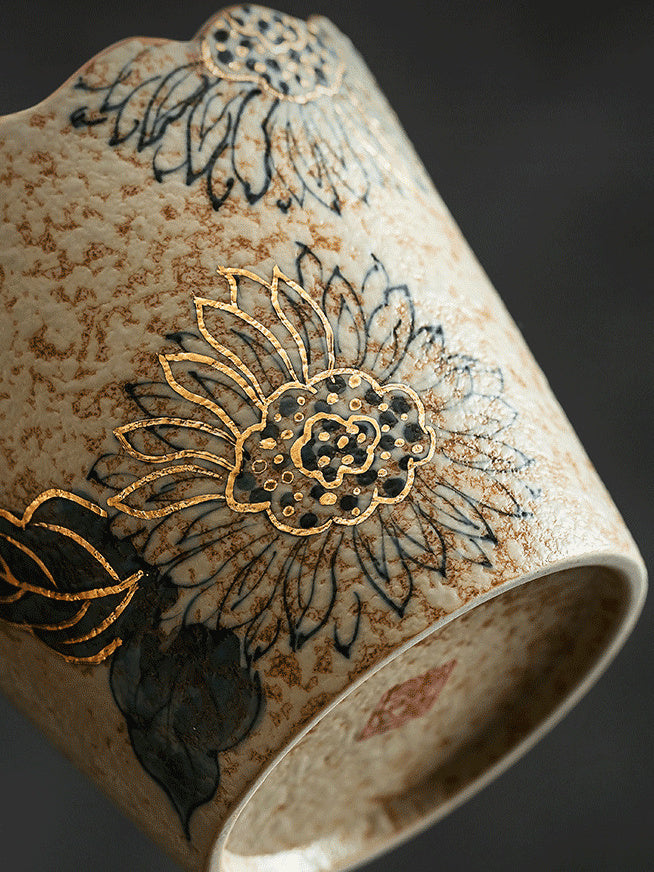 Close-up of the reactive glaze and gold-toned floral detailing on the ceramic cup
