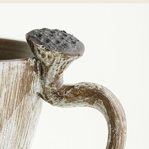 Close-up of the sculptural lotus pod handle and vertical brushwork on the ceramic coffee cup