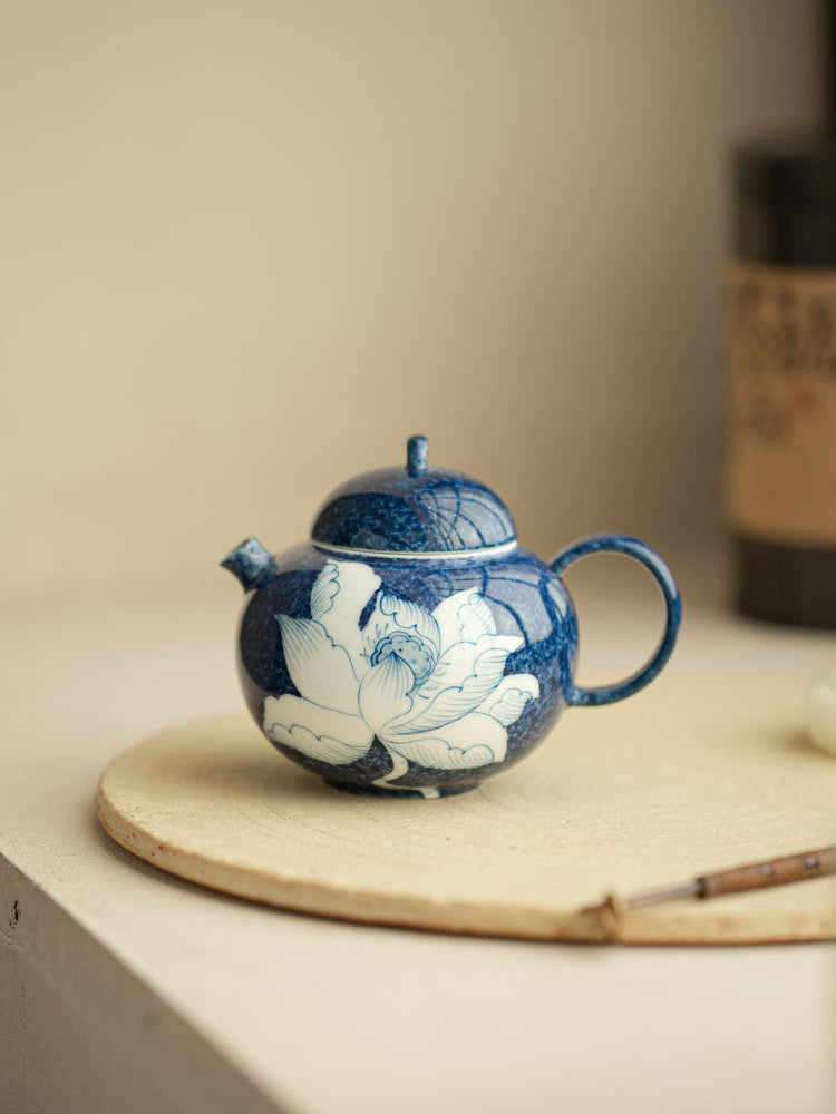 Chinese lotus ceramic teapot displayed on a light ceramic board
