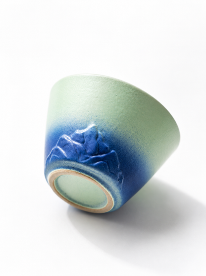 Pale green and deep blue teacup with raised mountain details
