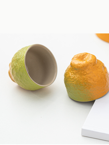 Matching tangerine-shaped ceramic teacups showing the glazed interior and fruit-like base