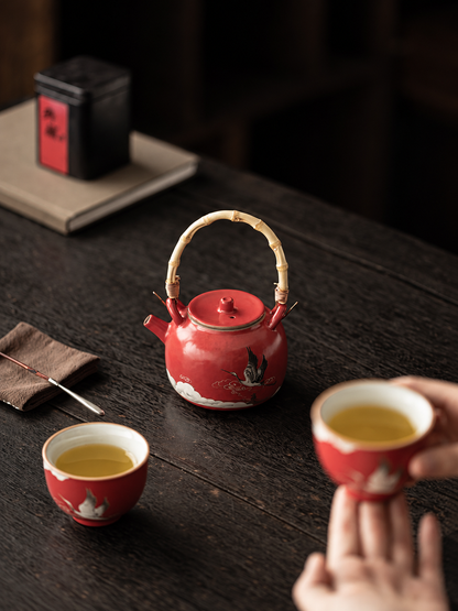 Two-person tea setting with a red crane teapot and matching ceramic cups

