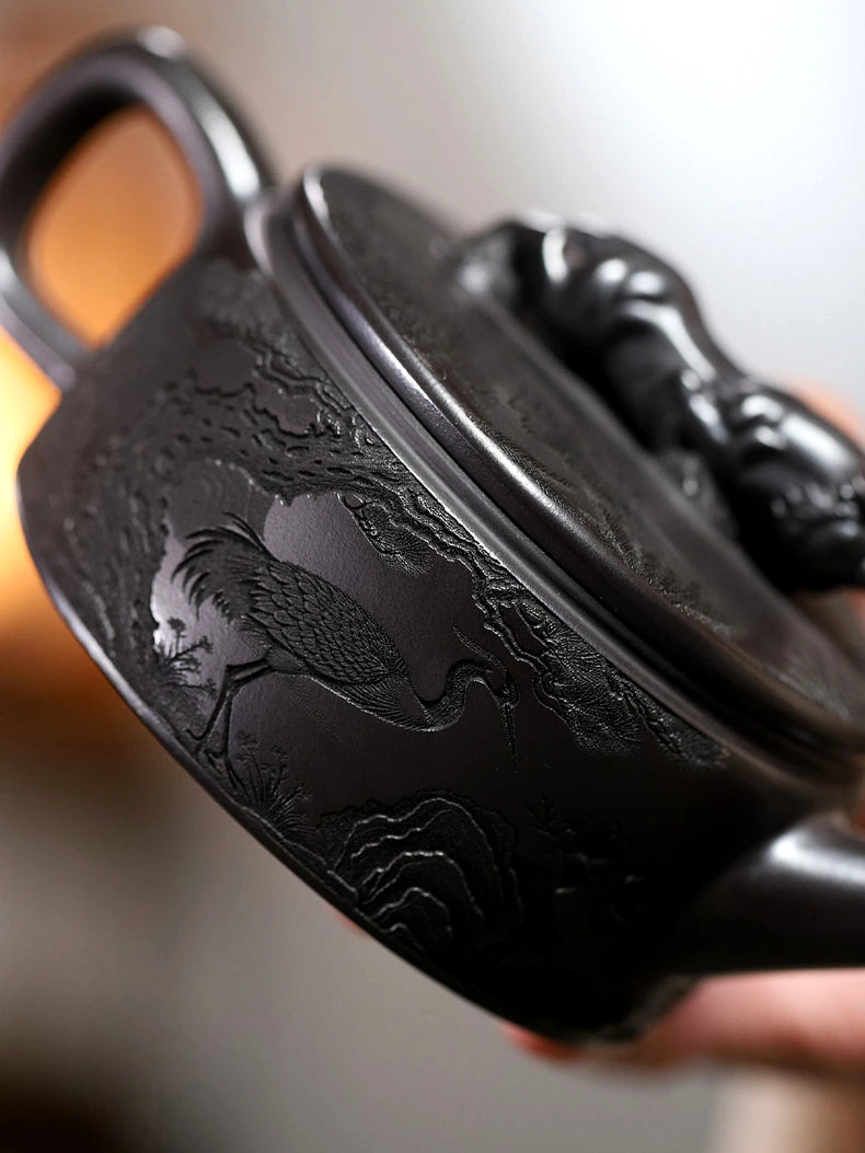 Angled close-up of crane, mountain, and landscape carving around the zisha teapot body