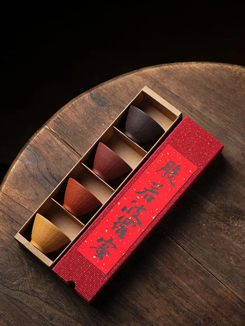 Angled overhead view of four zisha tea cups in the fixed red drawer-style gift box