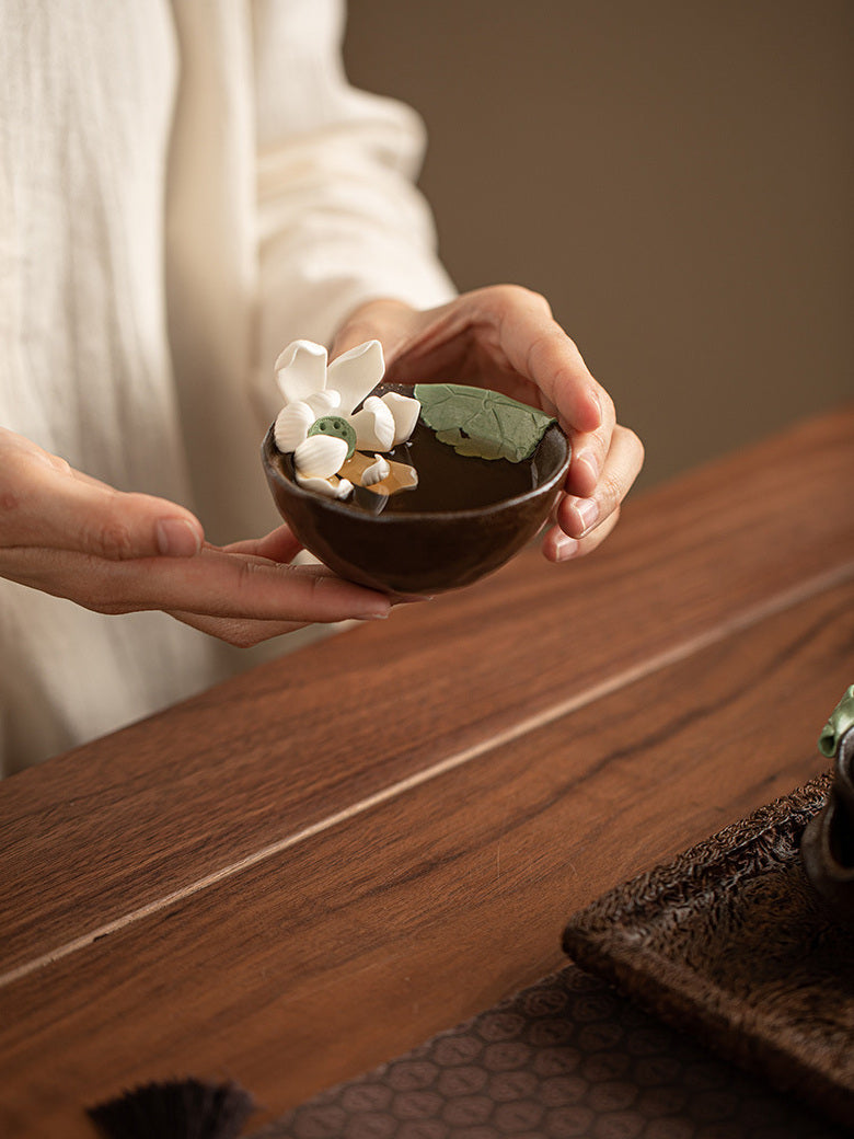 Person holding the handmade lotus ceramic tea cup with both hands