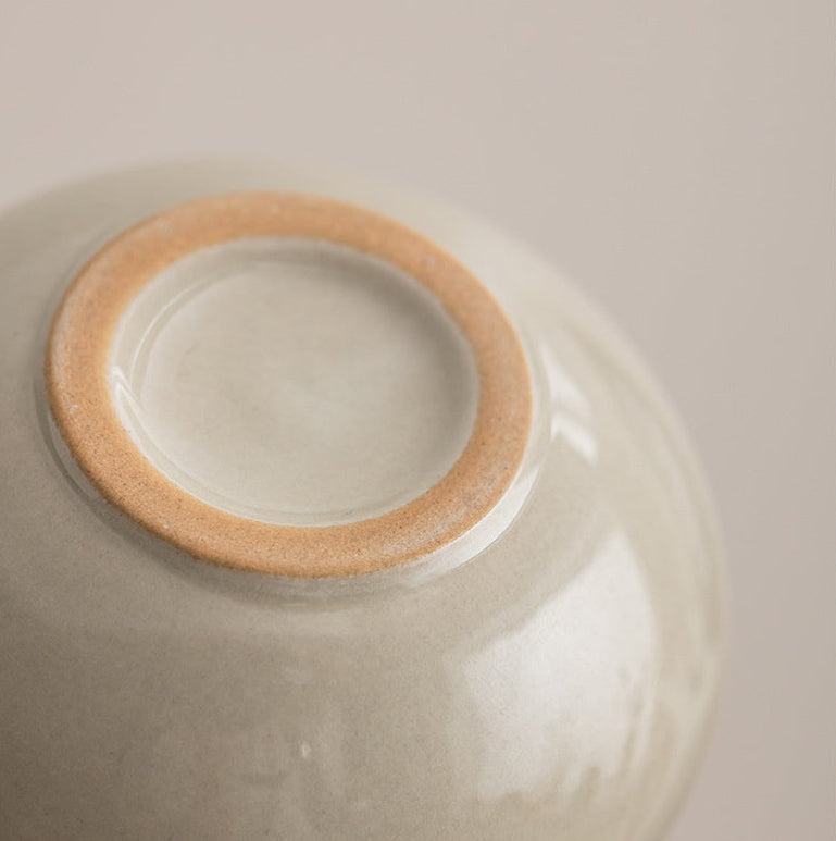 Close-up of the unglazed foot ring and softly varied glaze on the ceramic tea set
