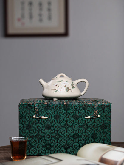 Floral side of the white duanni teapot displayed on a sample patterned gift box