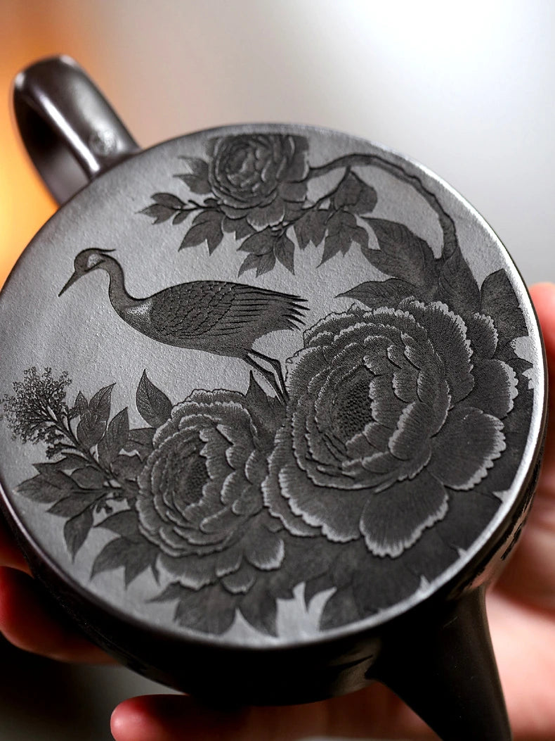 Angled close-up of crane, mountain, and landscape carving around the zisha teapot body