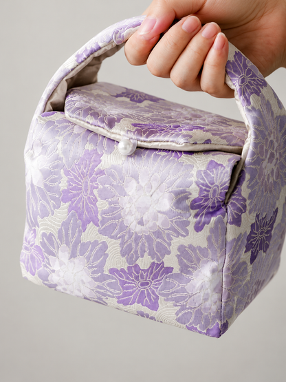 Close-up of the woven purple floral fabric and handle on the travel bag
