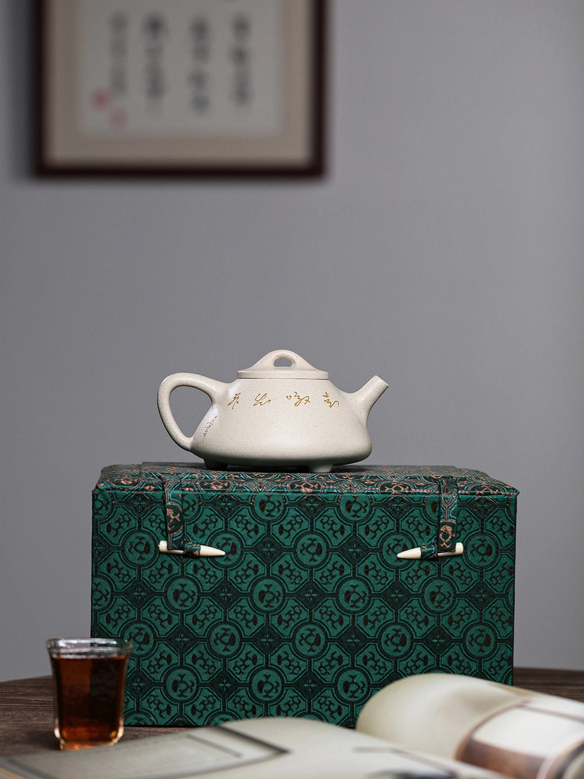 Calligraphy side of the white duanni teapot displayed on a sample patterned gift box