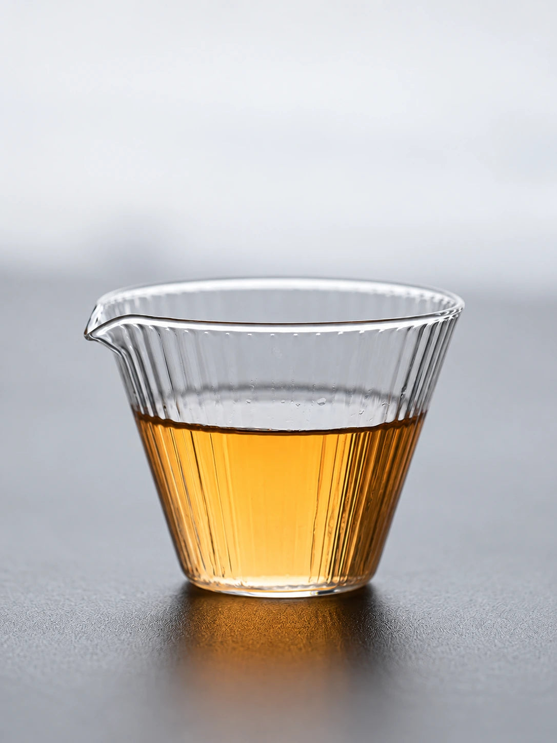 Clear high-borosilicate glass tea pitcher with ribbed sides and amber tea
