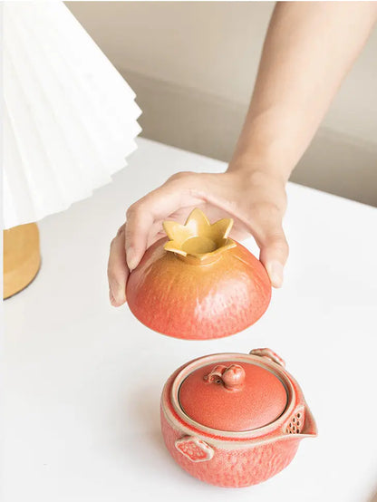 Host cup lifted above the matching coral pomegranate teapot
