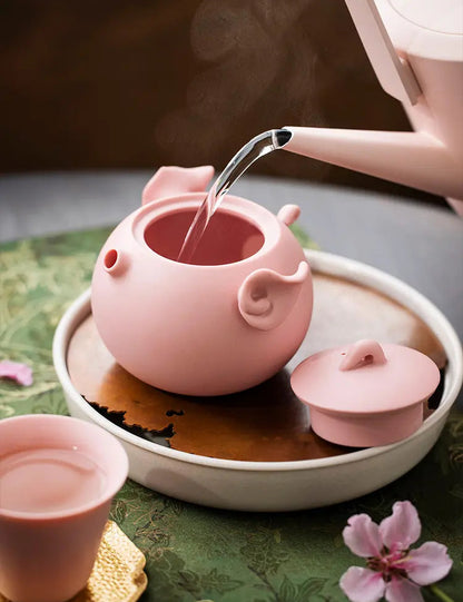 Hot water being poured into the open pink zisha pig teapot
