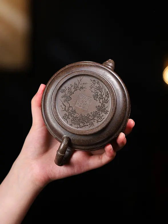 Hand holding the underside of a bamboo drum zisha teapot with its maker's mark