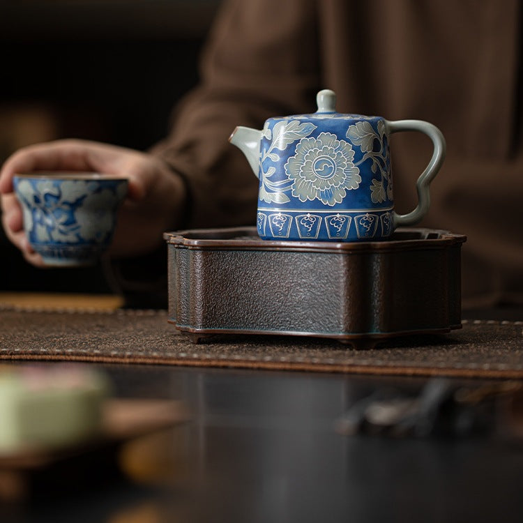 Blue peony teapot in a quiet tea setting as a person holds a cup
