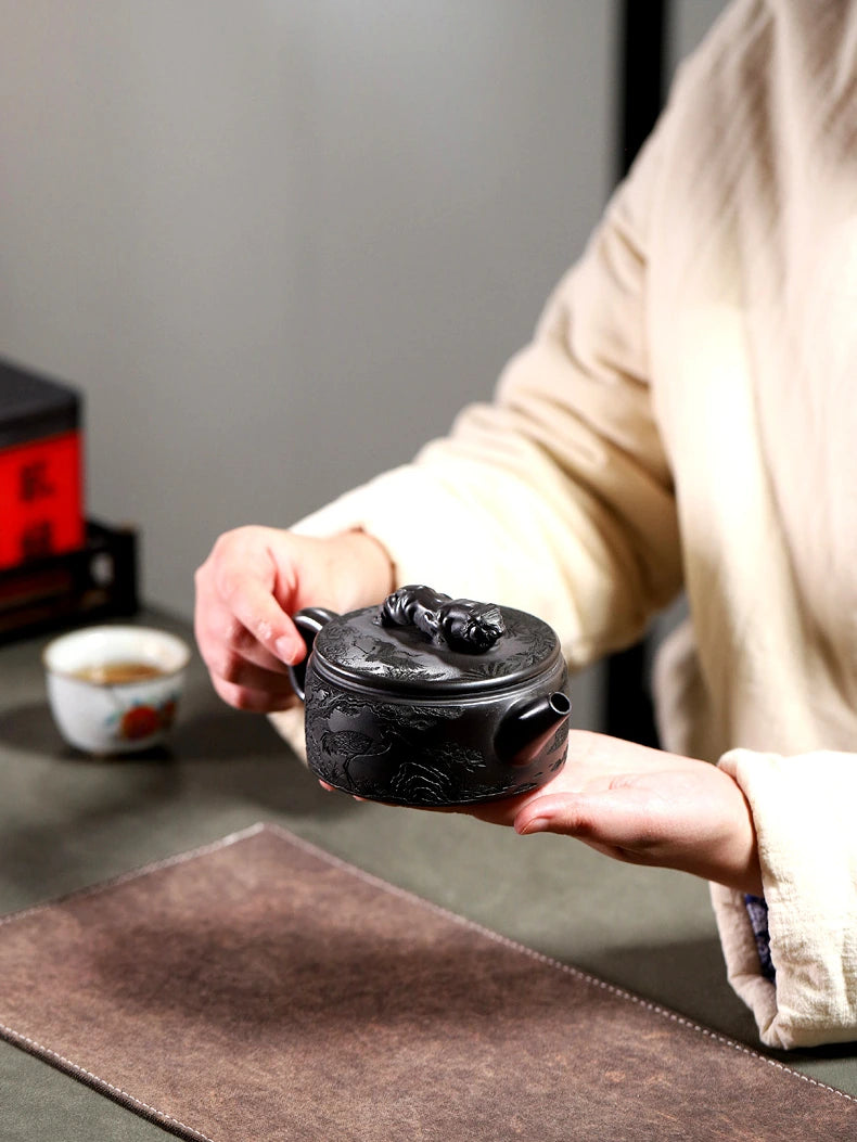 Hand lifting the tiger-knob lid from the low carved Yixing Hanwa teapot