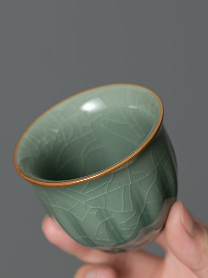 Close-up of a green crackle-glazed tasting cup with a warm brown rim
