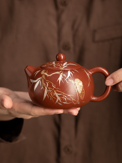 Handheld Xishi zisha teapot showing rounded form and cicada motif